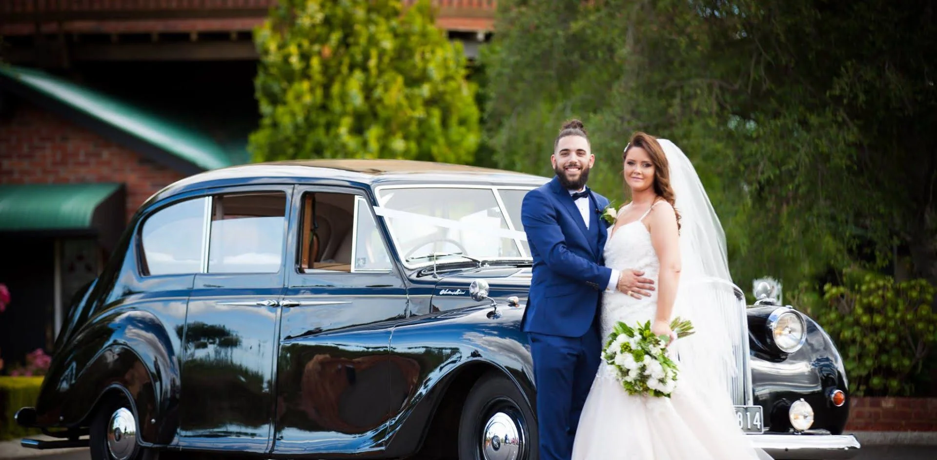 Bride and groom beside a vintage car at a Melbourne garden venue
