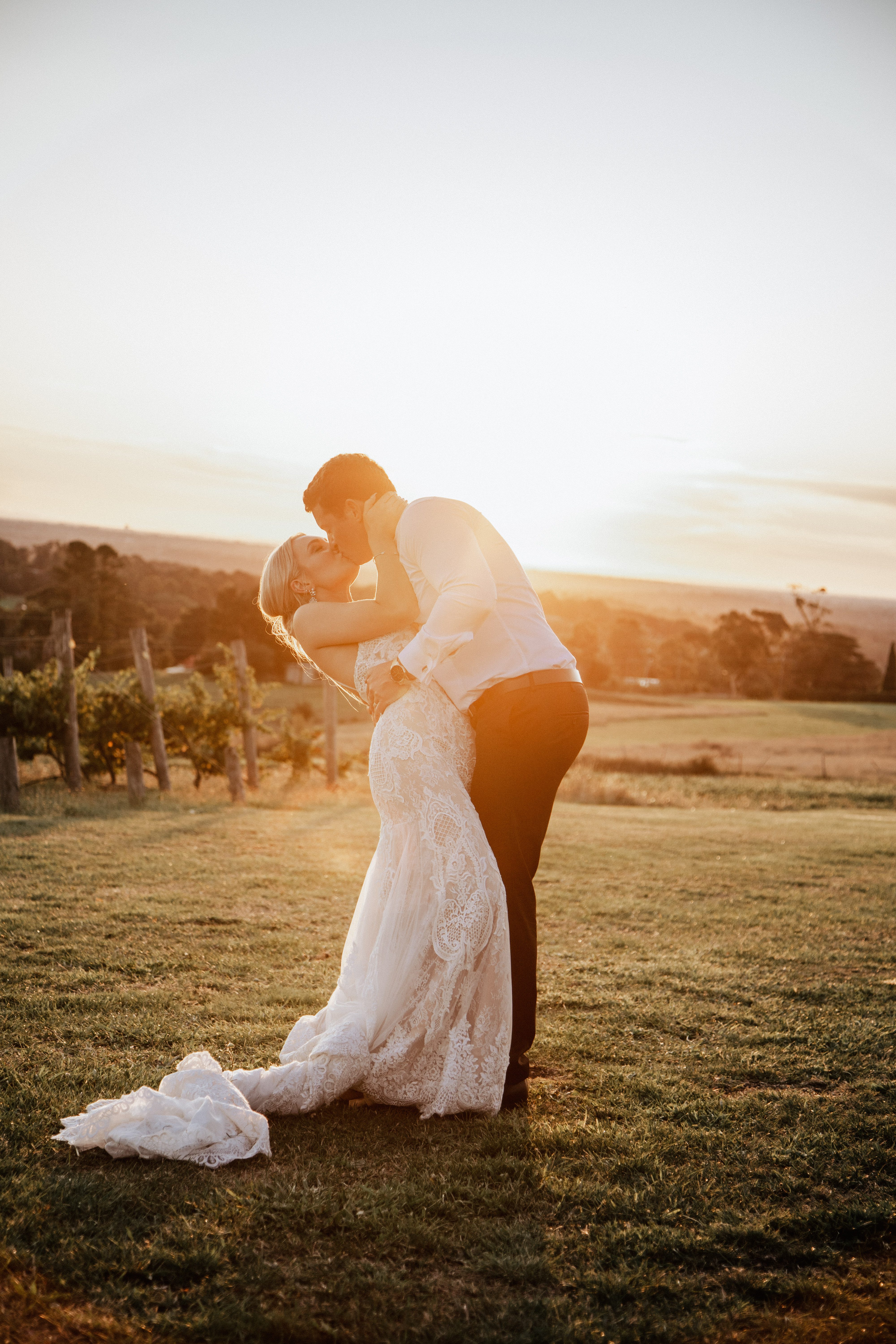 Groom dipping his bride for a kiss at sunset beside a Yarra Valley vineyard