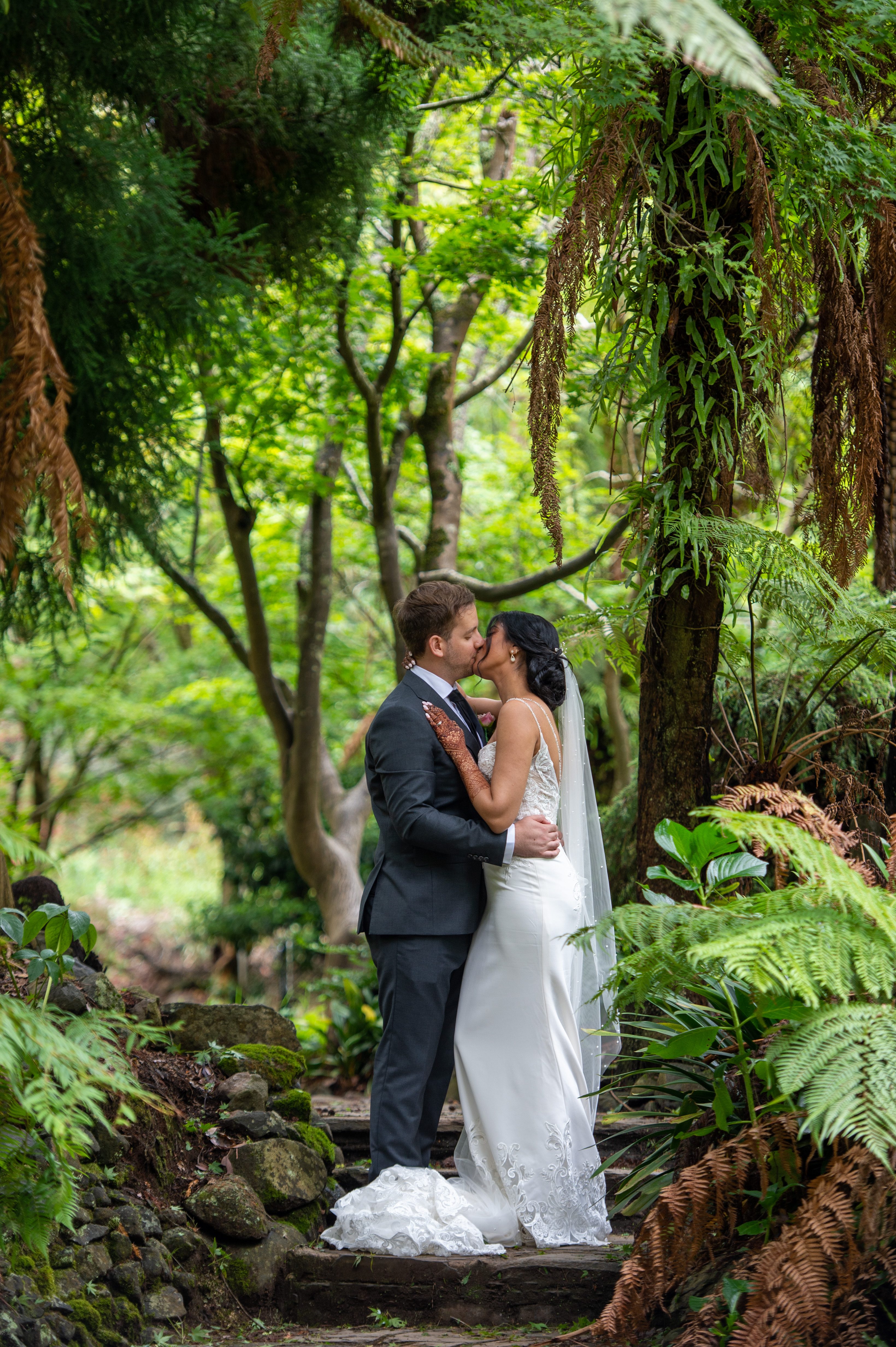 Bride and groom among tall forest trees in soft light