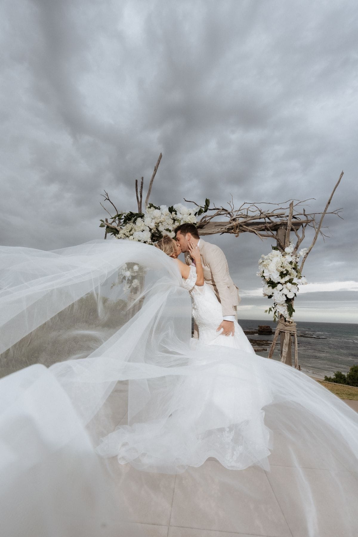 Bride beneath a floral arch with a flowing veil — Melbourne wedding