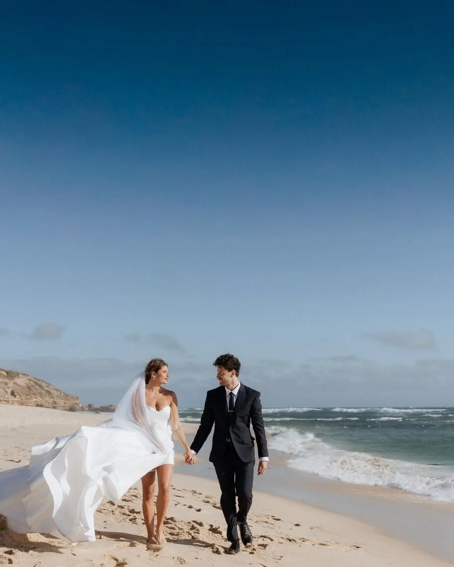 Bride and groom walking along a Melbourne bayside beach at golden hour