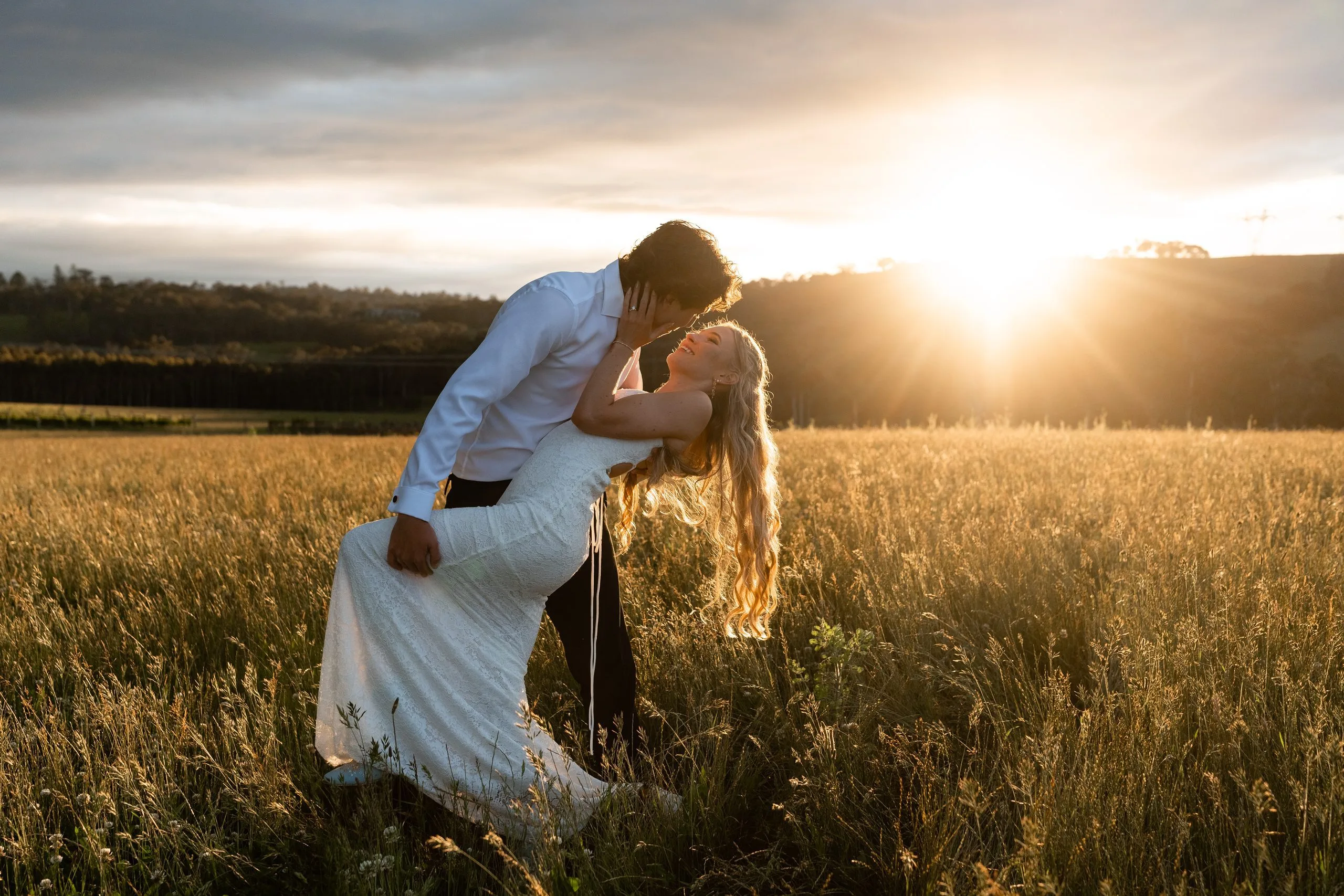 Bride and groom embracing in golden afternoon light in a Melbourne field