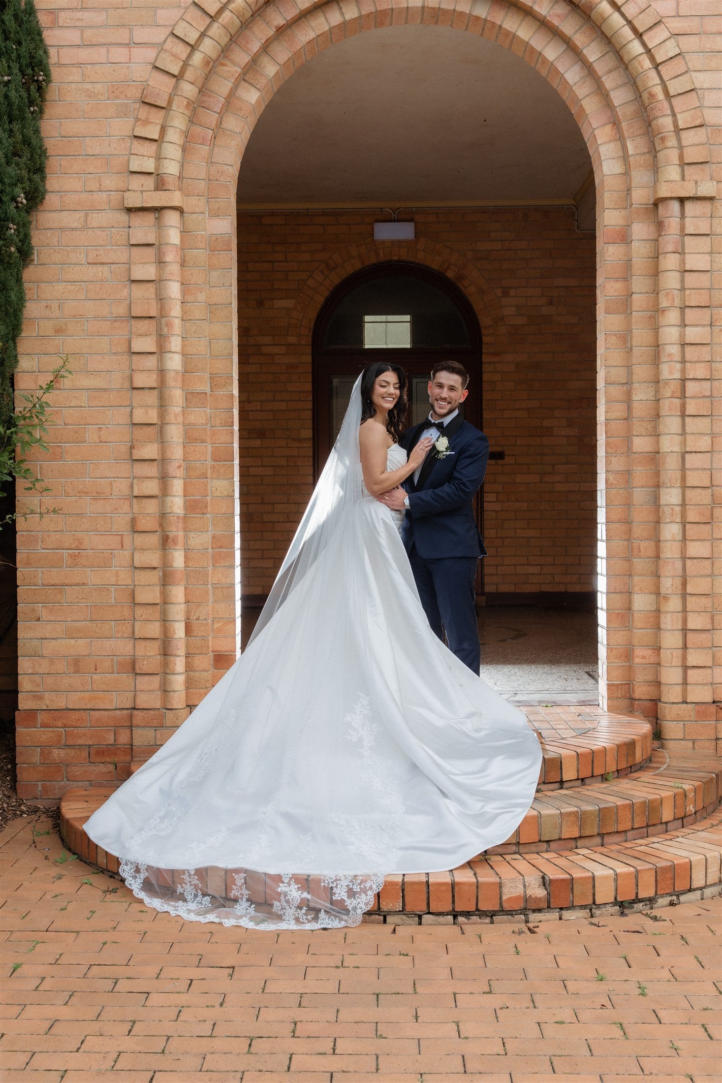 Afonso and Agnes smiling beneath a brick arch