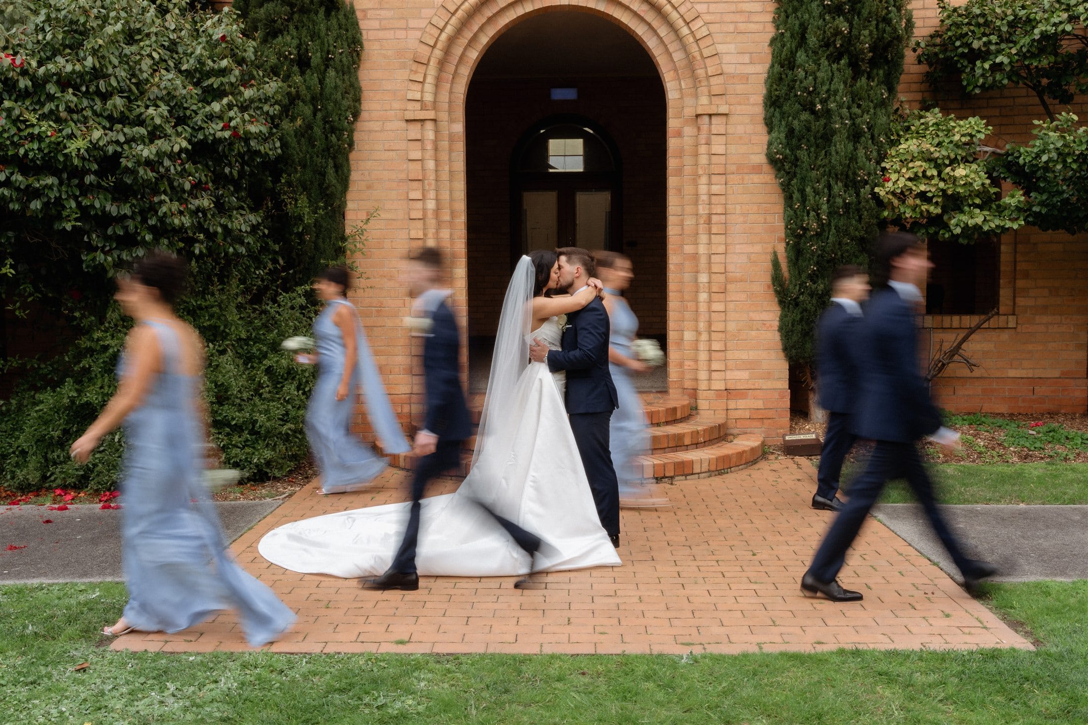 Afonso and Agnes kissing as their wedding party walks past